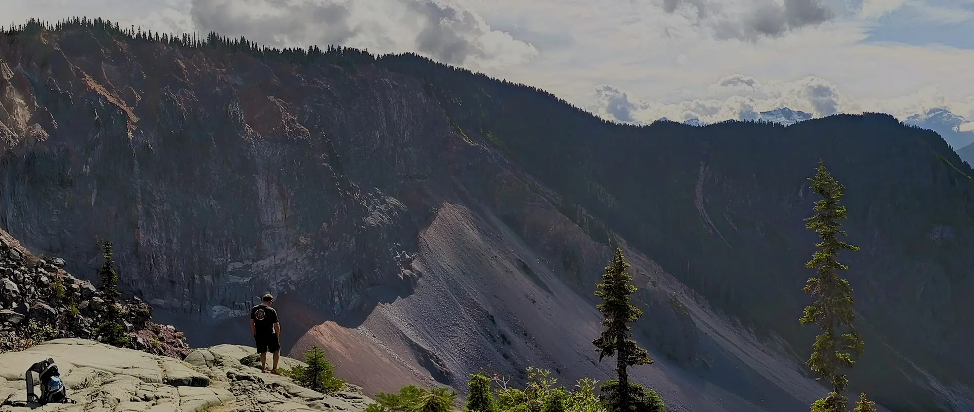 A mountain with trees and clouds in the background.