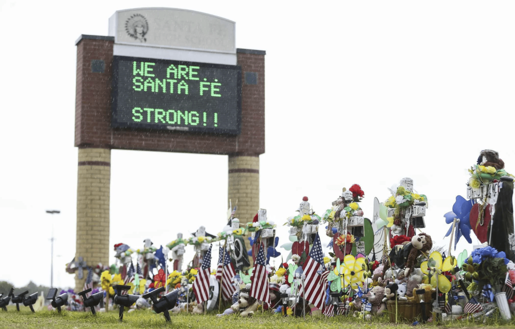A group of people standing around a building with flags.